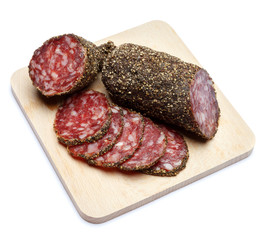 Dried organic salami sausage covered with pepper on wooden serving board