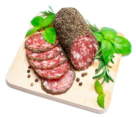 Dried organic salami sausage covered with pepper on wooden serving board