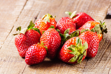 Red ripe juicy strawberries on old brown  wooden  background, closeup.