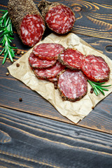 Dried organic salami sausage covered with pepper on wooden background