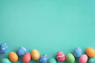 Happy Easter! Turquoise background with colorful easter eggs. Top view with copy space.
