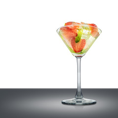 Mojito cocktail in martini glass with mint, strawberry and ice cubes isolated on mirror table and place for inscription. Clipping path