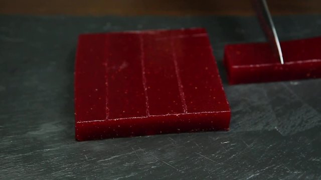 large piece of crimson marmalade cuts by knife into rows