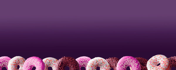set of purple donuts on a purple background with space for text.