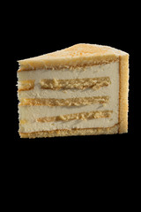 Fototapeta premium slice of tasty cake with vanilla cream. isolated over black background