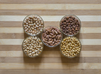 Five bowls of legumes on a chopping board