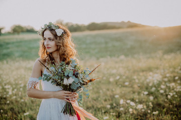 Beautiful young bride at sunset in green nature.
