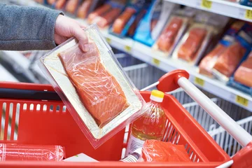 Fotobehang Pack of salmon in hand at store © Sergey Ryzhov
