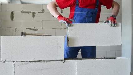 bricklayer builder working with autoclaved aerated concrete blocks. Walling