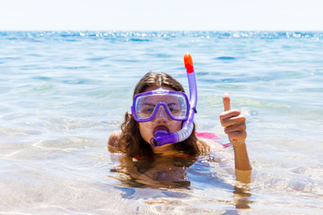 Woman on beach vacation holidays with snorkel lying in sea with snorkeling mask smiling happy...