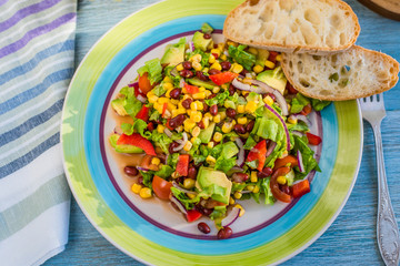 Traditional Vegetarian American Southwest Salad with vegetables, avocado, beans and corn on a rustic background