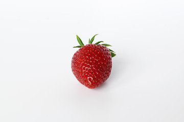 ripe strawberry with a green tail on a white background