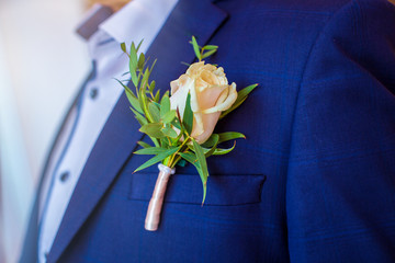 Boutonniere in form of rose on wedding suit of groom