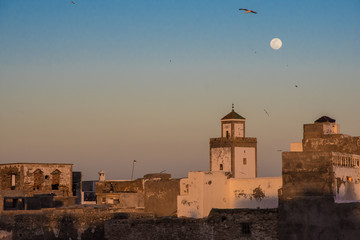Full moon rising during sunset mosque in Essaouira, Morocco