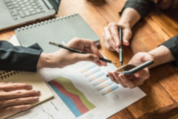 working woman are working at coffee shop they use mobile phone to search data about they's work from social network and  they have laptop , papers graph and note to help for work put on wooden table.