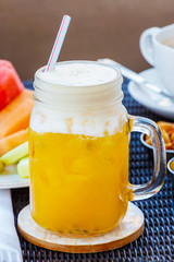 Tropical cocktail, mocktail, juice, refreshing drink from passion fruit in glass jar on table in cafe. Nuts, peanuts, olives, cappuccino coffee and fruits background.