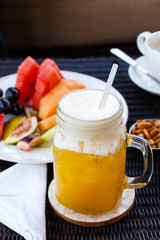 Passion punch cocktail. Tropical cocktail  juice refreshing drink from passion fruit in glass jar. Nuts, peanuts, cappuccino coffee and fruits background.