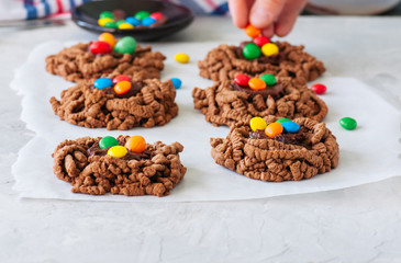 Chocolate bird's nest cookies decorated with colorful candies on a white background.