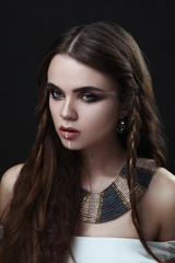 Beautiful model with creative makeup is deeply emotionally posing in a dark studio