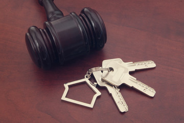 Judge gavel and keys with key holder on wooden table