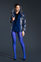 Stylish woman in blue pantyhose and transparent raincoat on dark background