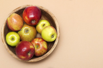 Ripe juicy apples in a wooden bowl on the table top view. Copy space