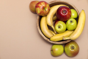 Group of healthy fresh fruit in a wooden bowl on the table. Copy space. Apples and bananas. Top view