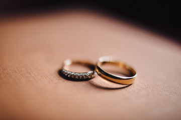 wedding rings of the bride and groom are on a wooden table