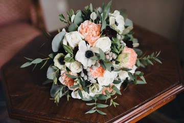 wedding bouquet of flowers and greens lies on a wooden table in the room
