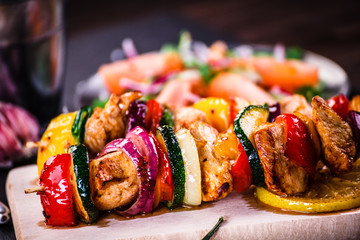 Kebabs - grilled meat with french fries and vegetables on wooden background