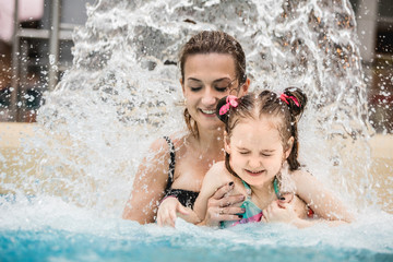 Woman and her daughter standing under a waterfall