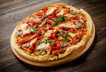 Pizza with ham and vegetables on wooden table