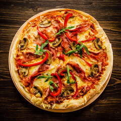 Pizza with ham and vegetables on wooden table
