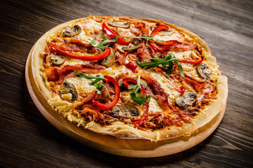 Pizza with ham and vegetables on wooden table