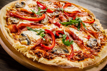 Pizza with ham and vegetables on wooden table