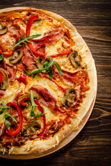 Pizza with ham and vegetables on wooden table