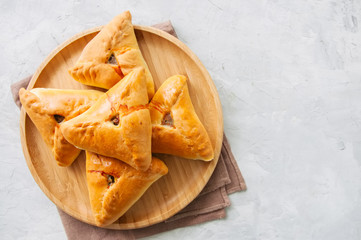 Homemade uchpuchmak (samsa) with meat and potato served on a wooden plate on a white  background. Top view and copy space.