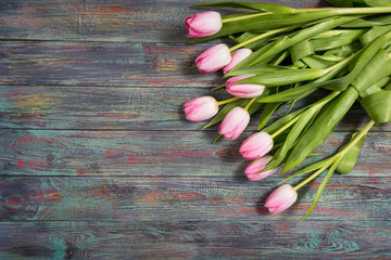 Border from bright pink tulips flowers on wooden background. Selective focus, place for text