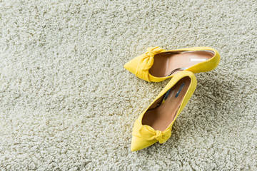 top view of stylish yellow high heels on carpet