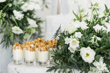 Desserts served in glasses besides white bouquet of flowers
