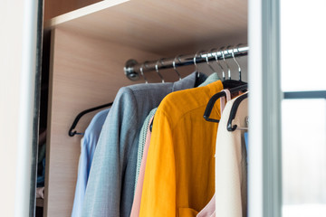 colorful female clothes hanging on rack in cabinet