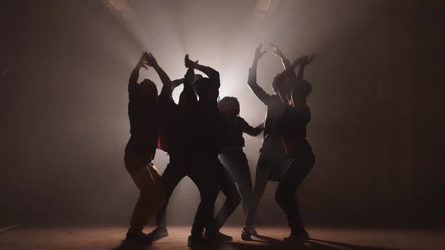 Group of street dancers performing different moves on the dark street.