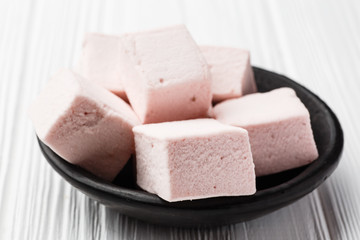 Pink marshmallow on white wood table