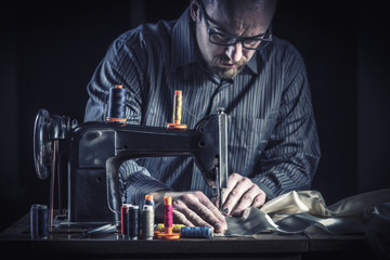 portrait and details of a tailor at work with an old and traditional sewing machine. manual and ancient work.