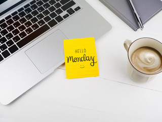 Hello Monday text with smiley face on sticky note on desk
