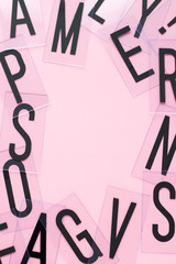 Frame of english letters with copy space on pastel pink background. Alphabet study, abc, education or business concept. Top view. Close-up.