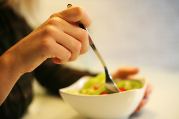 Naklejka na ściany i meble Close-up of woman’s hands eating fresh salad.