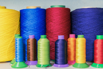 Closeup of coils with colored threads on the shelf in sewing workshop