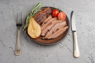 Braised duck breast in honey with rosemary, pear and tomatoes.