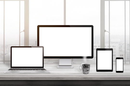 Responsive web site design mockup. Computer displaz, laptop, tablet and smart phone on office desk. Window and sun light in background.